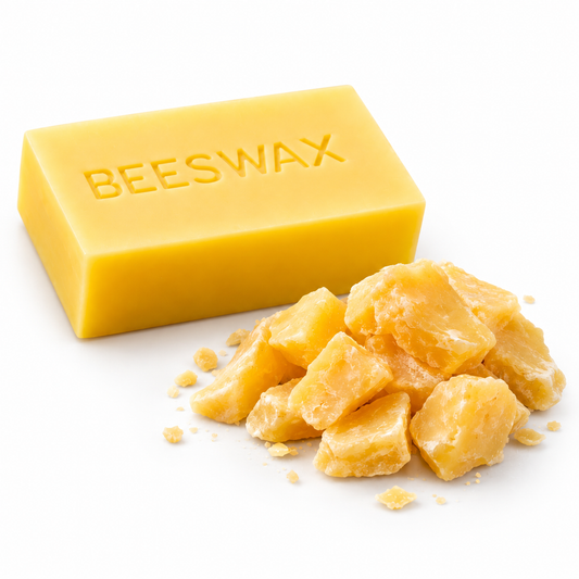 Golden beeswax block and loose beeswax pieces on a white background